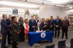 library staff and government representatives standing around NJ governor murphy signing a new law